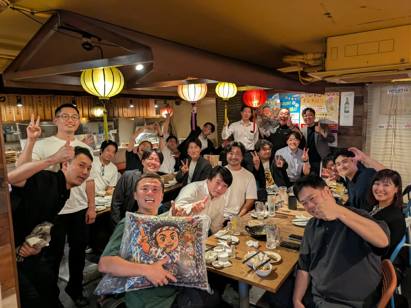提灯の下がる居酒屋で、参加者が集まった集合写真