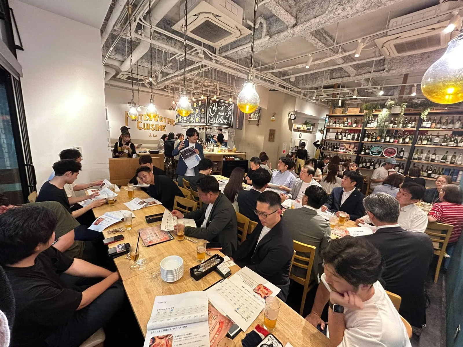 長い食卓を囲んで資料を読む、満席の会