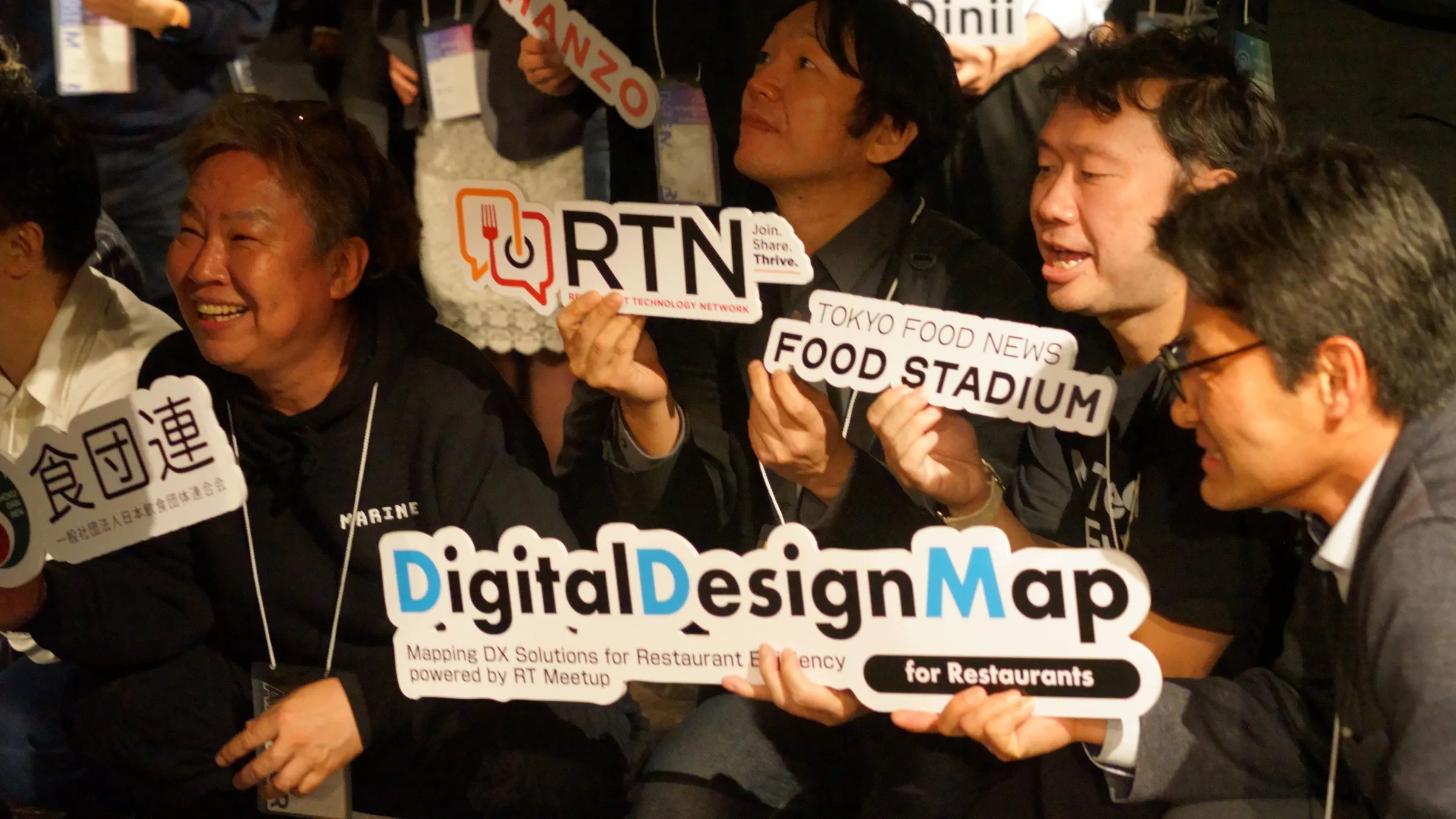 2025年3月の総会・懇親会で、「DigitalDesignMap」などの札を掲げる参加者
