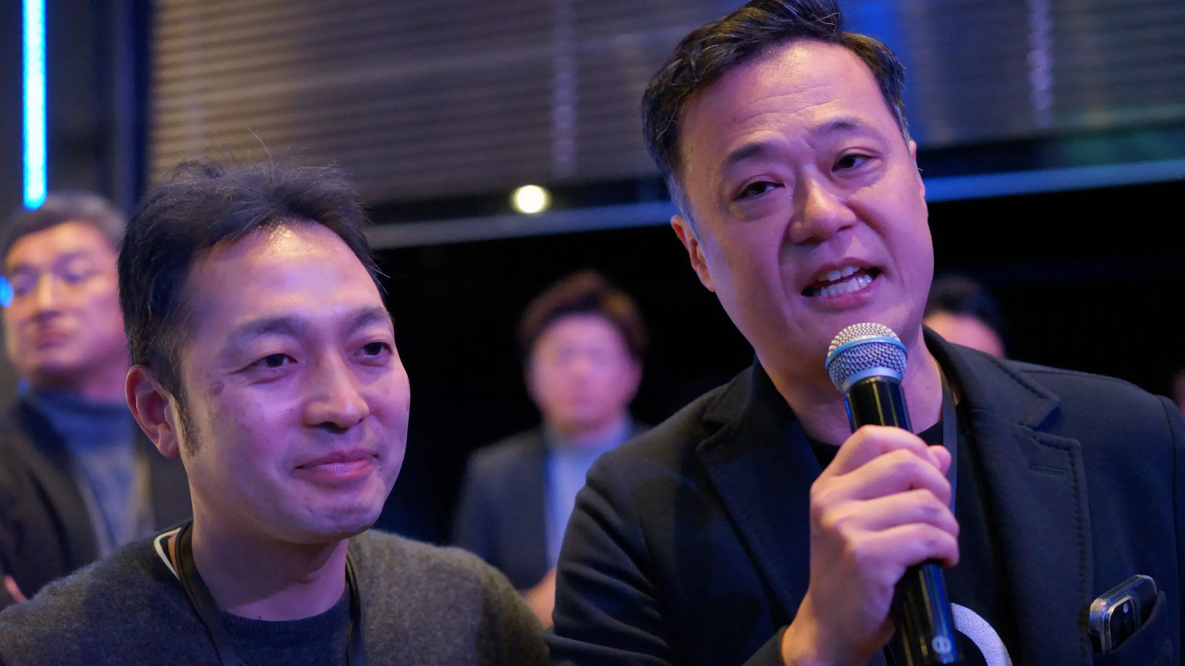 2026年2月20日、銀座で開いた年次総会で、マイクを持って話す参加者と、隣で聞く参加者